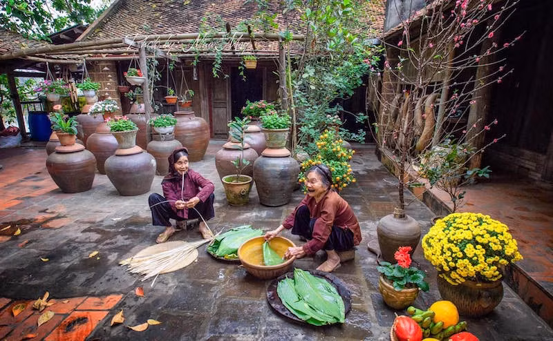 Các cụ bà sửa soạn gói bánh chưng bên ngôi nhà cổ ở Làng cổ Đường Lâm. (Ảnh: Ngọc Diệp)