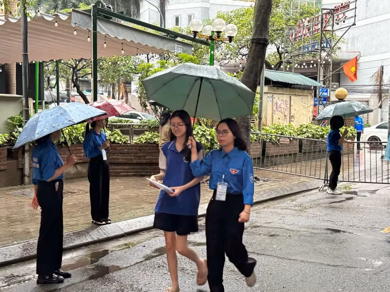 Lực lượng thanh niên tình nguyện hỗ trợ thí sinh dự thi kỳ thi tuyển sinh vào lớp 10 không bị ướt. (Ảnh: KHÁNH THY)
