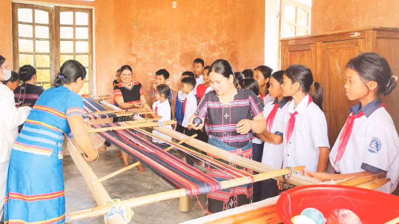 Những người thợ lành nghề hướng dẫn các em học sinh kỹ thuật lên khung dệt thổ cẩm.