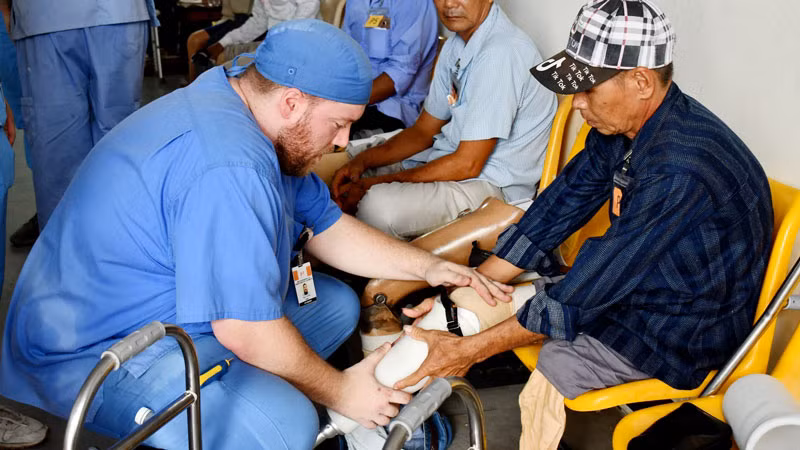 Thành viên Đoàn thiện nguyện Mercer On Mission lắp chân giả cho người khuyết tật.