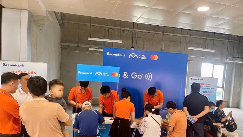 Nhân viên ngân hàng hỗ trợ hành khách làm thẻ đi tàu không dùng tiền mặt tại các nhà ga.