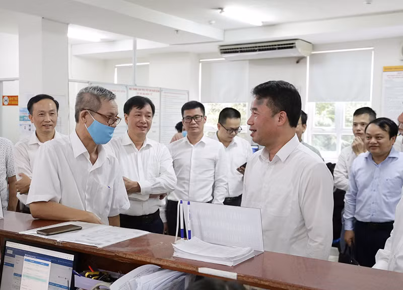 Tổng Giám đốc Bảo hiểm xã hội Việt Nam Nguyễn Thế Mạnh (hàng đầu, bên phải) trao đổi với người dân đến làm việc tại phòng "một cửa" (Bảo hiểm xã hội TP Hồ Chí Minh). (Ảnh TÂM TRUNG)