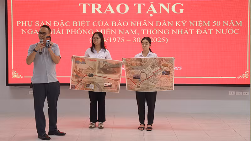 Phóng viên Văn phòng đại diện Báo Nhân Dân tại Tuyên Quang hướng dẫn các em học sinh quy trình quét mã QR để trải nghiệm phụ san.