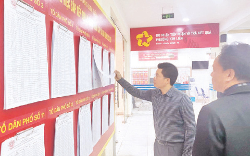Lãnh đạo quận Đống Đa kiểm tra việc niêm yết danh sách cử tri lấy ý kiến về việc sắp xếp các đơn vị hành chính tại phường Kim Liên. (Ảnh PHƯƠNG THẢO)