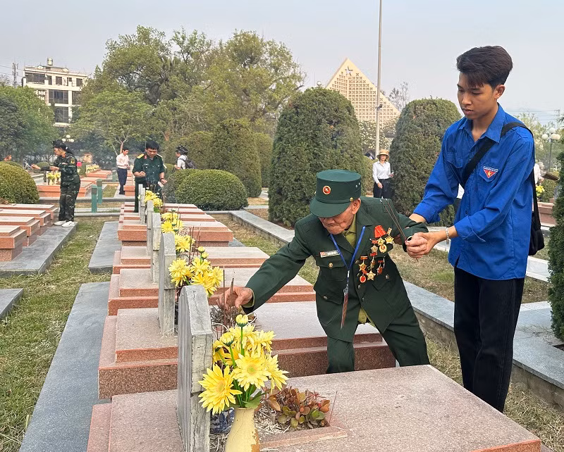 Bước chân không còn khỏe, người lính năm xưa nhờ đoàn viên thanh niên dìu đến từng phần mộ thắp hương viếng đồng đội.