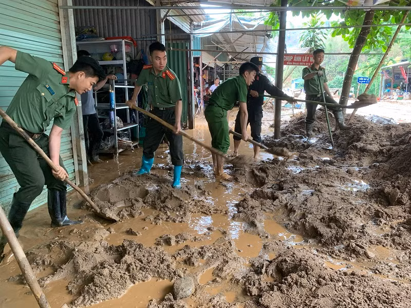 Cán bộ, chiến sĩ Công an huyện Điện Biên Đông đang nỗ lực giúp nhân dân bản Suối Lư hót bùn đất tràn vào nhà.