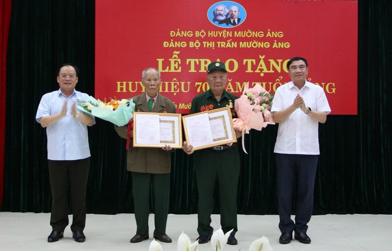 Đồng chí Trần Quốc Cường, Bí thư Tỉnh ủy Điện Biên và đồng chí Mùa A Sơn, Phó Bí thư Thường trực Tỉnh ủy Điện Biên tặng hoa, chúc mừng 2 chiến sĩ Điện Biên vinh dự được nhận Huy hiệu 70 năm tuổi Đảng.