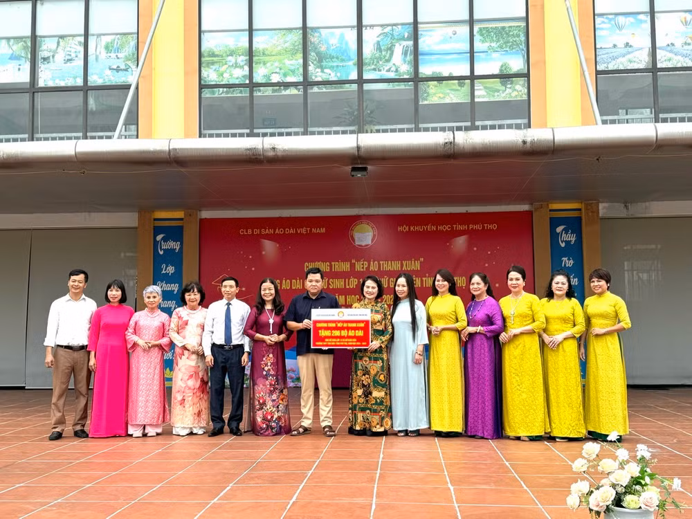 Đại diện Câu lạc bộ Di sản áo dài Việt Nam trao biểu trưng 206 bộ áo dài cho Trường Phổ thông trung học huyện Tân Sơn. (Ảnh: Ban tổ chức)