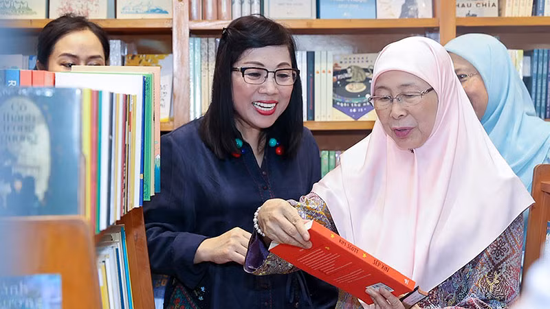 Bà Lê Thị Bích Trân, Phu nhân Thủ tướng Phạm Minh Chính và bà Dato’ Seri Dr. Wan Azizah binti Dr. Wan Ismail, Phu nhân Thủ tướng Anwar Ibrahim xem sách, thích thú khi được trải nghiệm không gian đọc ngoài trời.