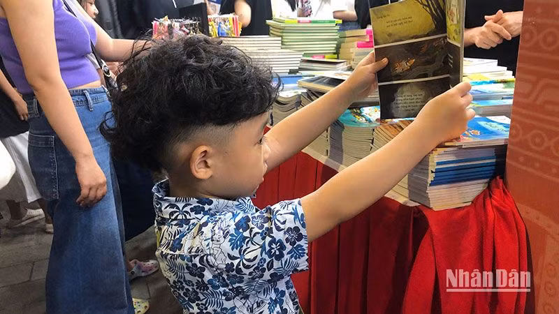Em bé say sưa xem sách tại Hội sách Hà Nội 2022.