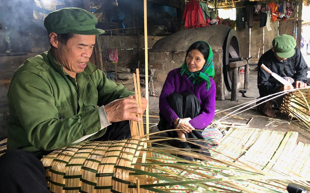 Ông Lâm A Liên và ông Lâm A Diện đang đan gùi trong căn bếp nhà mình.