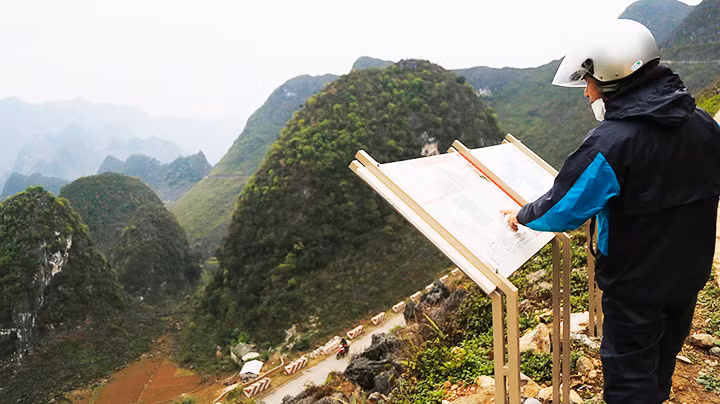 Du khách xem thông tin giới thiệu về tuyến đi bộ Vách đá trắng, sản phẩm du lịch mới trên đèo Mã Pì Lèng (Hà Giang). Ảnh: K.MINH