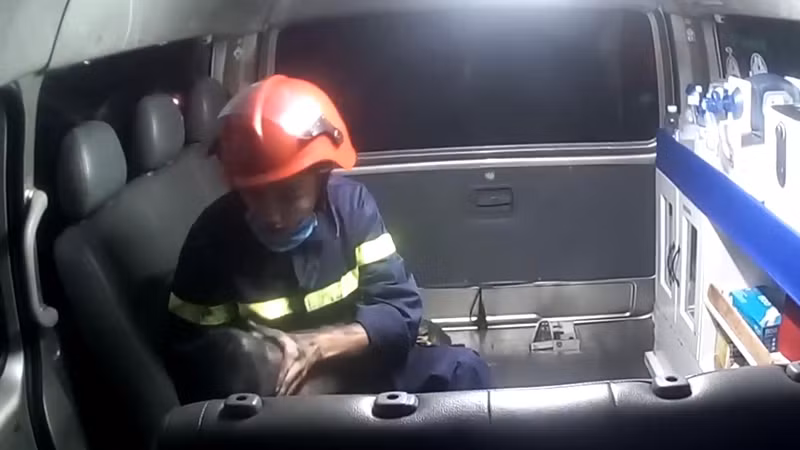 Hình ảnh chiến sĩ chữa cháy Trần Văn Quỳnh đang sơ cứu cháu bé trên xe cứu thương.