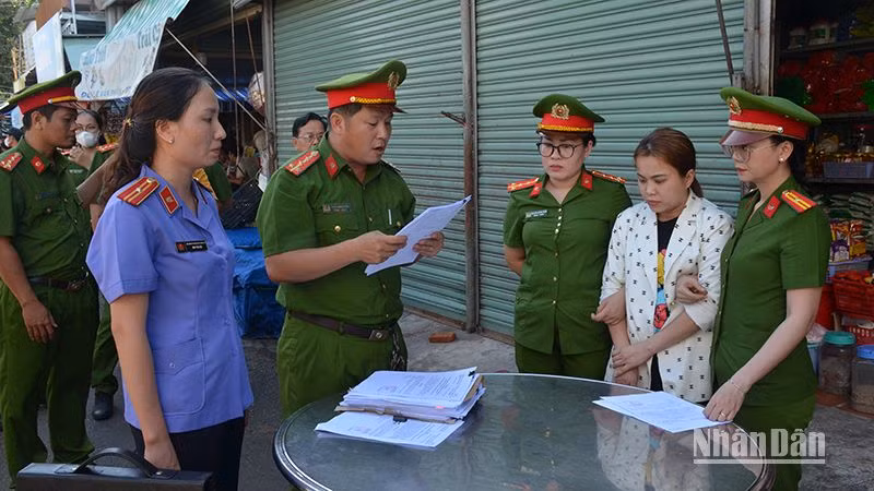Cơ quan cảnh sát điều tra Công an thành phố Phan Thiết đọc Quyết định khởi tố bị can đối với Ngô Thị Loan Chi (áo trắng hoa), về tội “Lừa đảo chiếm đoạt tài sản”.