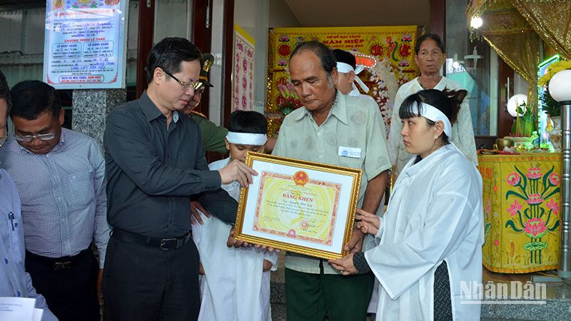 Chủ tịch UBND tỉnh Bình Thuận Đoàn Anh Dũng (áo sậm màu) trao cho thân nhân gia đình anh Nguyễn Hữu Đốn Bằng khen truy tặng anh Nguyễn Hữu Đốn vì đã có hành động dũng cảm quên mình cứu người, cứu tài sản của nhân dân.