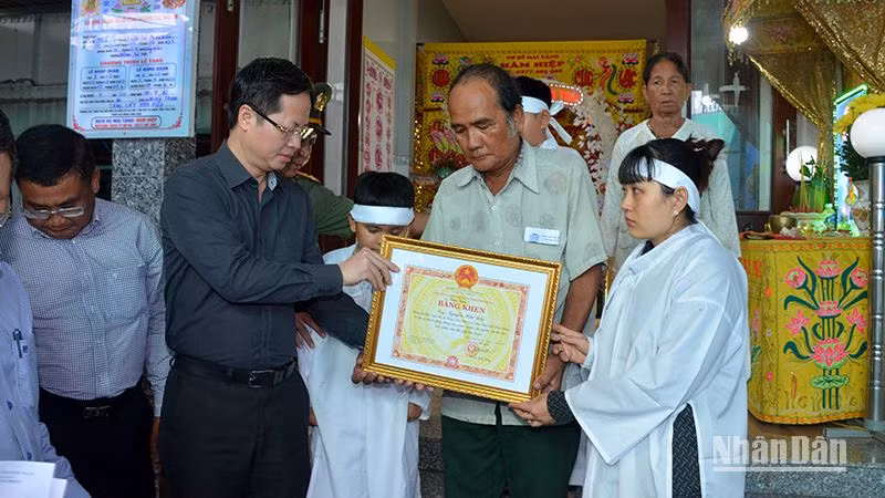 Chủ tịch UBND tỉnh Bình Thuận Đoàn Anh Dũng (áo sậm màu) trao cho thân nhân gia đình anh Nguyễn Hữu Đốn Bằng khen truy tặng anh Nguyễn Hữu Đốn vì đã có hành động dũng cảm quên mình cứu người, cứu tài sản của nhân dân.