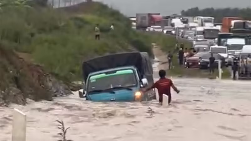 Một xe tải nhẹ cố vượt qua đoạn ngập nhưng bị nước dâng cao làm trôi dạt vào lề.