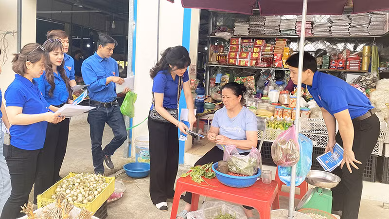 Ðoàn viên thanh niên Sở Thông tin và Truyền thông tỉnh Bắc Kạn hướng dẫn tiểu thương ở chợ sử dụng mã QR thanh toán trực tuyến. (Ảnh THU TRANG) 