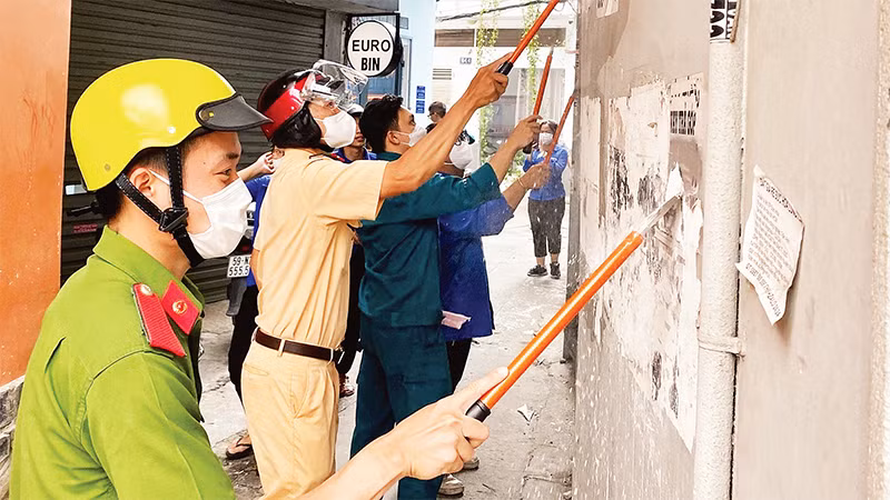 Công an, cảnh sát giao thông và các lực lượng phối hợp bóc gỡ các mẫu quảng cáo, tờ rơi dán sai nơi quy định. (Ảnh CTV) 