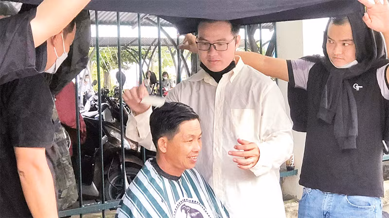 Anh Nguyễn Xuân Hiếu (áo trắng) cùng nhóm bạn trẻ cắt tóc miễn phí cho người dân.