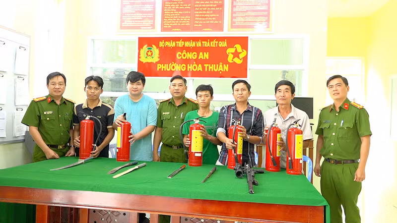 Người dân giao nộp vũ khí tại Công an phường Hòa Thuận và nhận bình chữa cháy. (Ảnh: Công an cung cấp)