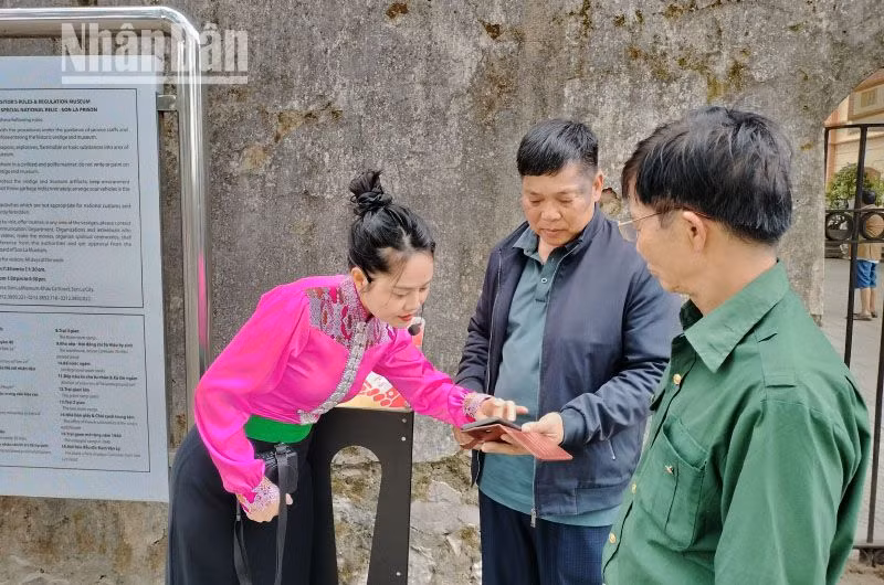Hướng dẫn viên tại Khu di tích Quốc gia đặc biệt Nhà tù Sơn La đang hướng dẫn khách du lịch tương tác với công nghệ số không dây để truy cập vào trang web “Yêu lắm Việt Nam”.
