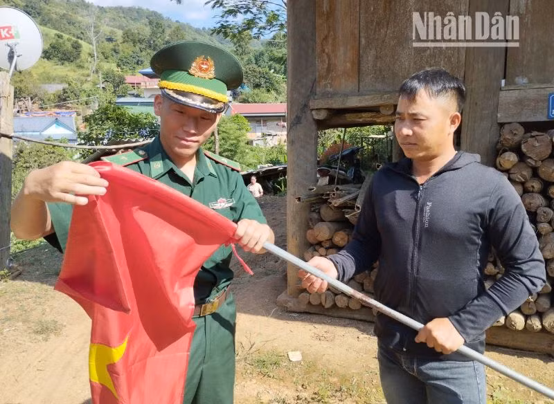 Cán bộ, chiến sĩ Đồn Biên phòng cửa khẩu Lóng Sập tặng cờ Tổ quốc cho người dân bản Bó Sập, xã Lóng Sập, huyện Mộc Châu treo chào đón ngày Tết Độc lập. 