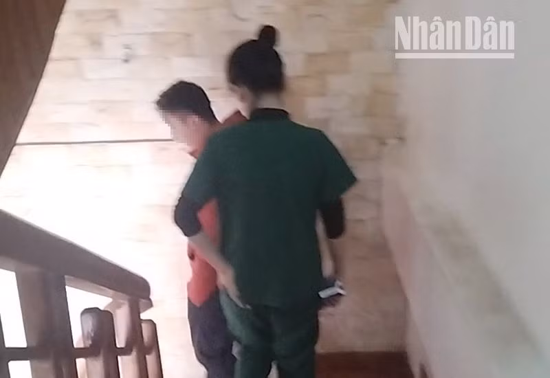 Một người đàn ông vừa điều trị xong ở khu vực tầng 3 của địa chỉ số 27 Tô Hiệu đang di chuyển cùng nhân viên điều trị xuống tầng 1 (ảnh cắt từ clip).