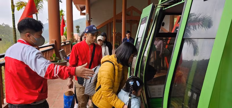 Các du khách được nhân viên hướng dẫn đi cáp treo lên chùa Ngọa Vân.