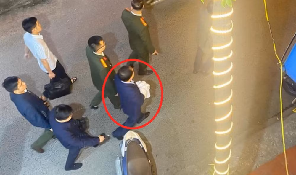 Ông Nguyễn Đình Đương (khoanh đỏ) bị áp giải khỏi nhà riêng. (Ảnh: Báo Công an nhân dân)