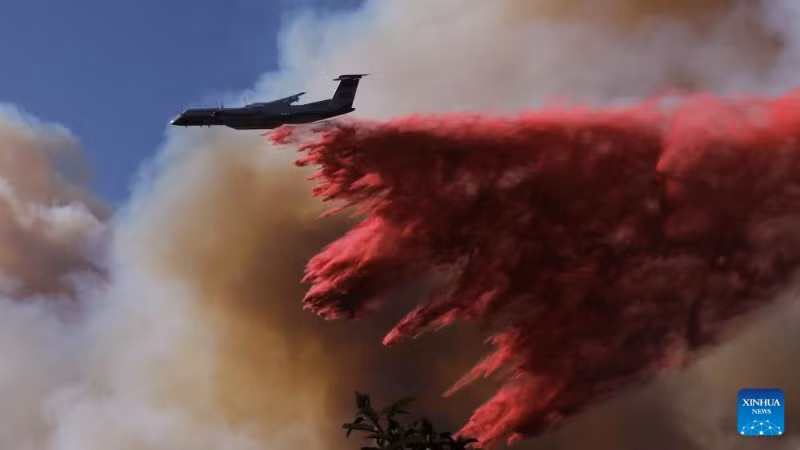 Một chiếc máy bay chữa cháy thả chất chống cháy để ngăn chặn đám cháy rừng lan rộng hơn. (Ảnh: Tân Hoa xã)