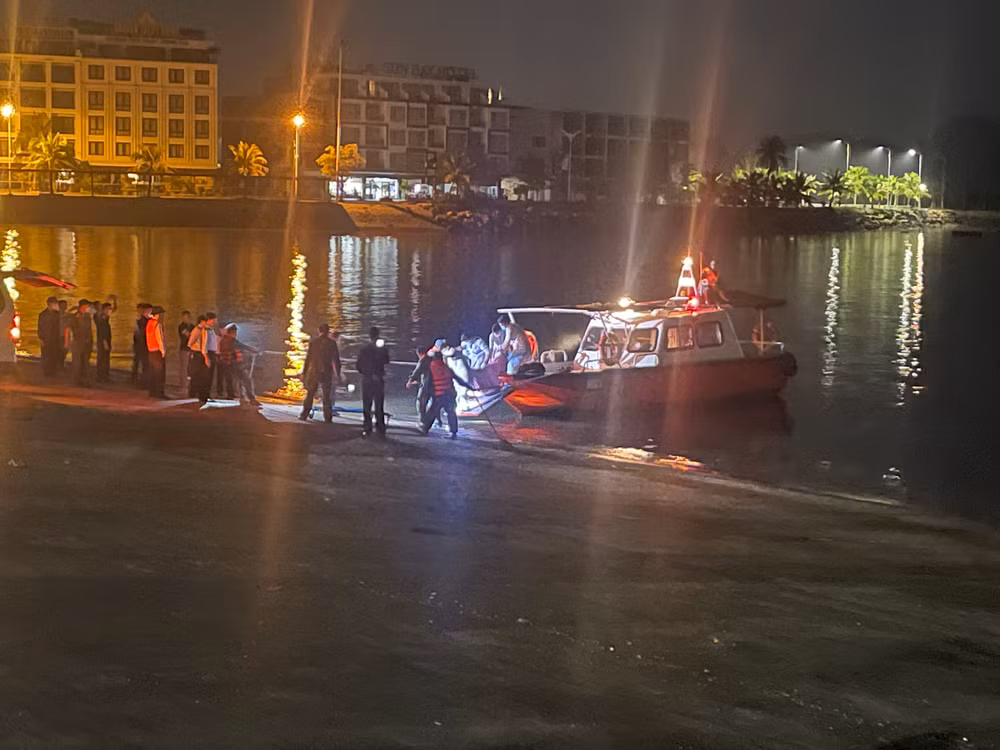 Các lực lượng chức năng đưa thi thể nạn nhân vào bờ. (Ảnh: Phạm Công)