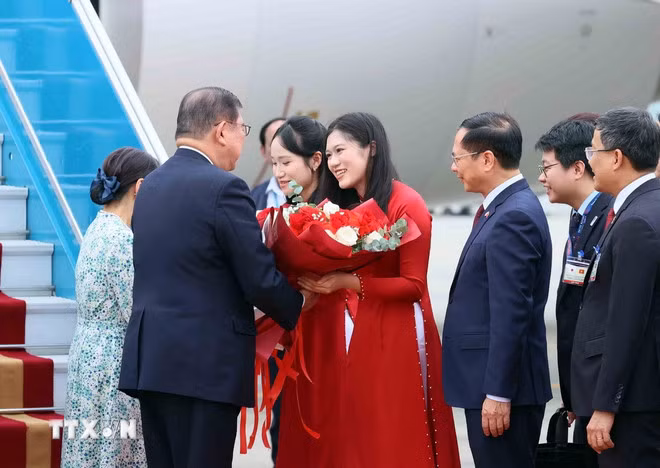 Thiếu nữ Hà Nội tặng hoa, chào mừng Thủ tướng Nhật Bản Ishiba Shigeru và Phu nhân thăm chính thức Việt Nam. (Ảnh: TTXVN)