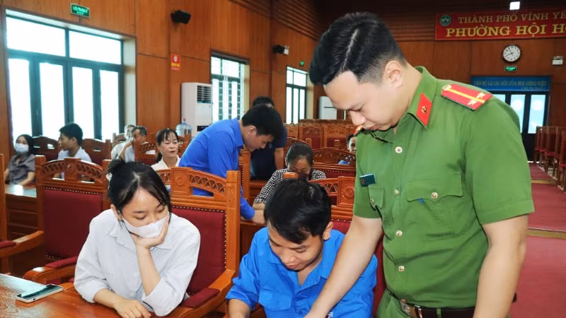 Thanh niên thành phố Vĩnh Yên hướng dẫn người dân sử dụng ứng dụng VneID. (Ảnh: Dương Hà)