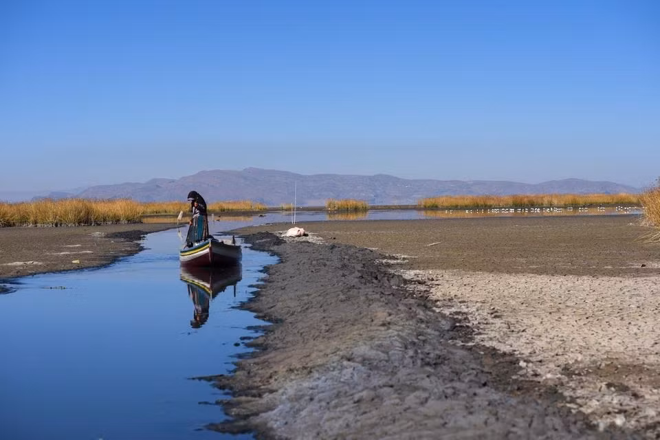 Một ngư dân chèo thuyền qua con nước hẹp gần bờ hồ Titicaca. Ảnh: Reuters.