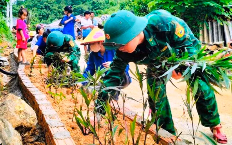 Thanh niên cùng lực lượng vũ trang trồng hoa bên đường nội bản Con Dao, xã Quang Chiểu.