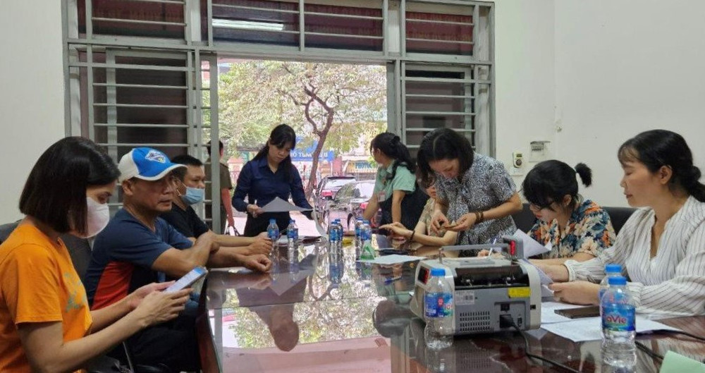 Những người dân chịu ảnh hưởng bởi vụ cháy nhận tiền hỗ trợ. (Ảnh: Việt Tuấn)