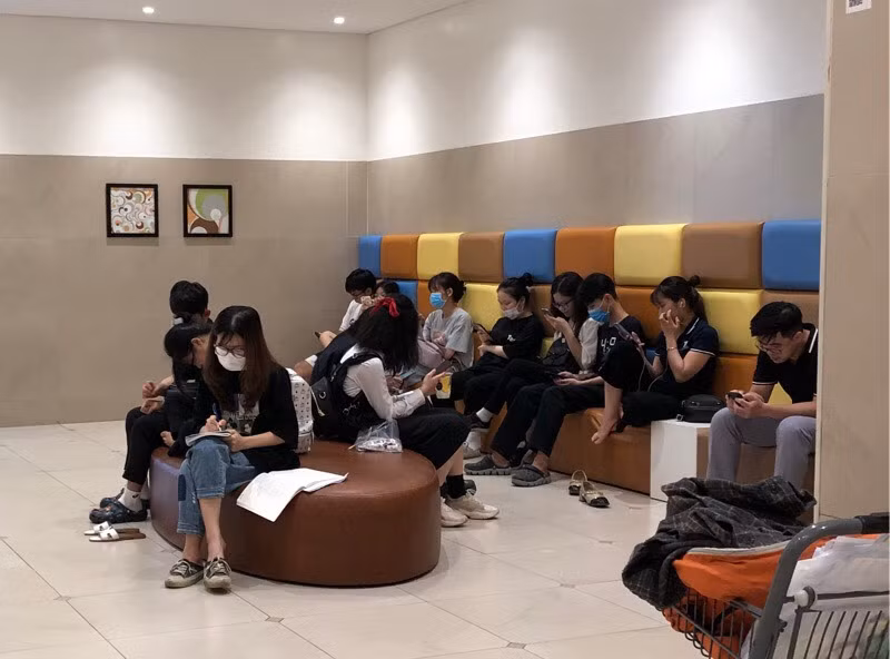 Thanh niên túm tụm ngồi xem điện thoại hoặc tranh thủ làm bài tập.