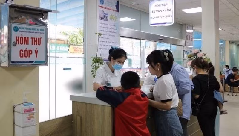 Nhân viên y tế tiếp đón và hướng dẫn người bệnh đăng ký khám bệnh tại Bệnh viện đa khoa Hà Đông. (ẢNH: DIỆU LINH)