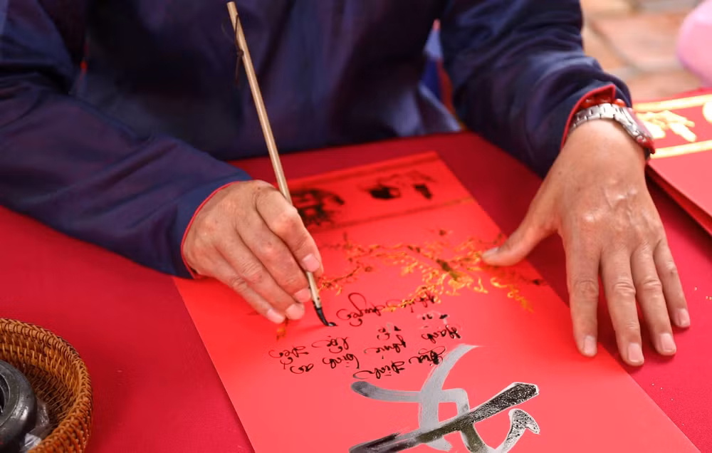 Thầy đồ viết chữ thư pháp cho khách tham quan. (Ảnh: Uyển Nhi)