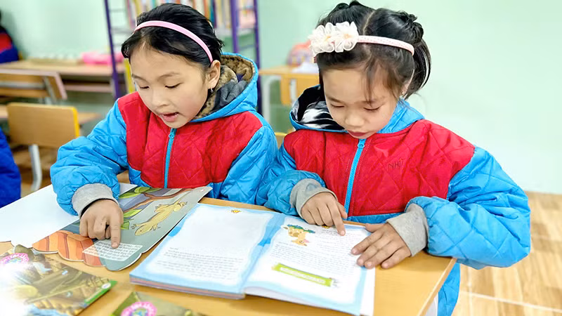 Các em học sinh đọc sách tại thư viện của Trường Phổ thông dân tộc bán trú Tiểu học Ngam La. (Ảnh NFVC)