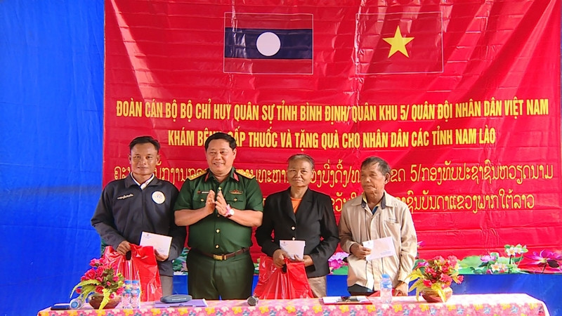 Đại tá Nguyễn Xuân Sơn, Phó Chính ủy Bộ Chỉ huy Quân sự tỉnh Bình Định tặng quà cho nhân dân ở cụm bản La Nhao, huyện Xá Mắc Khi Xay, tỉnh Attapu.