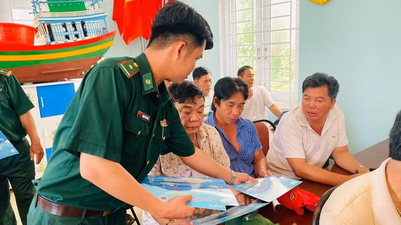 Cán bộ Đồn Biên phòng Mỹ An cấp phát tờ rơi cho ngư dân.