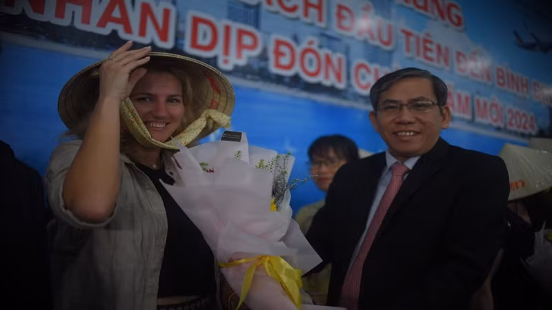 Du khách nước ngoài vui vẻ đón nhận hoa và quà mừng năm mới tại sân bay Phù Cát.