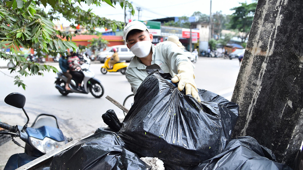 Thành viên nhóm Hà Nội Xanh dọn rác tại khu vực cầu Mậu Lương, quận Hà Đông, thành phố Hà Nội. (Ảnh MỸ HÀ) 