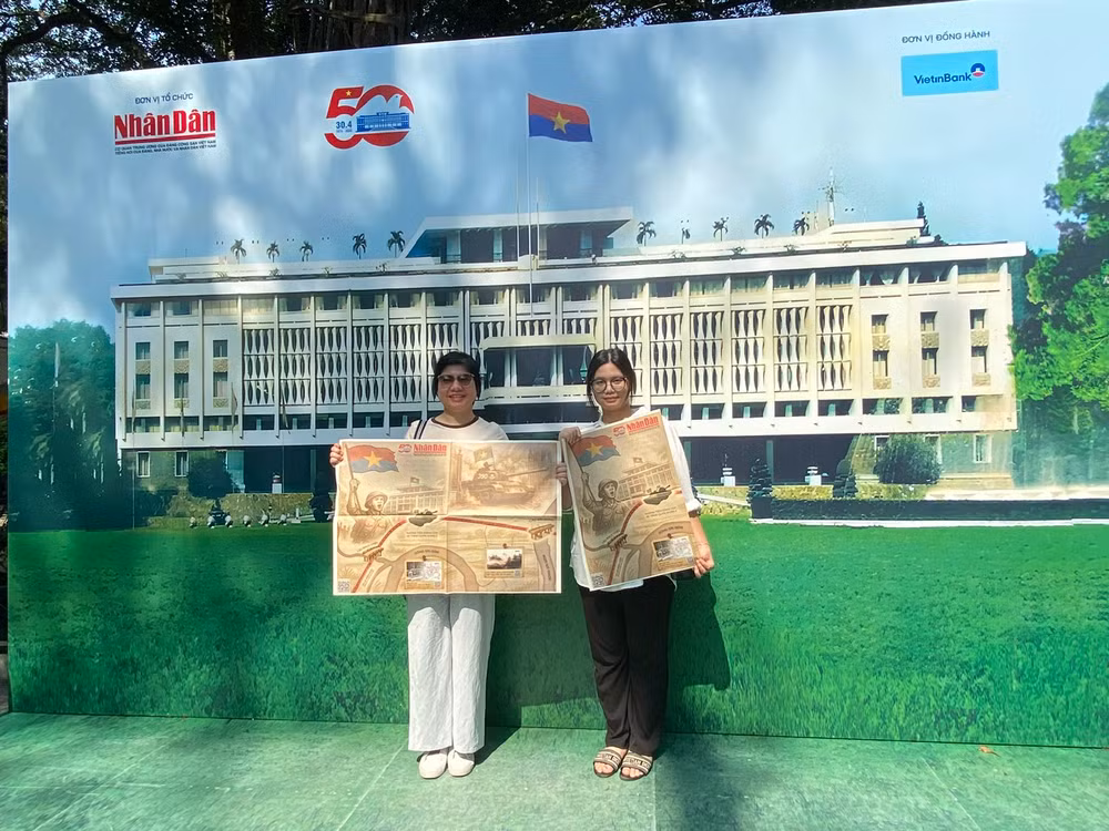 Chị Nguyễn Phương Thảo, ở quận Hoàng Mai, Hà Nội, cùng con gái chụp ảnh lưu niệm với phụ san trên tay. (Ảnh: ĐỖ THOA)