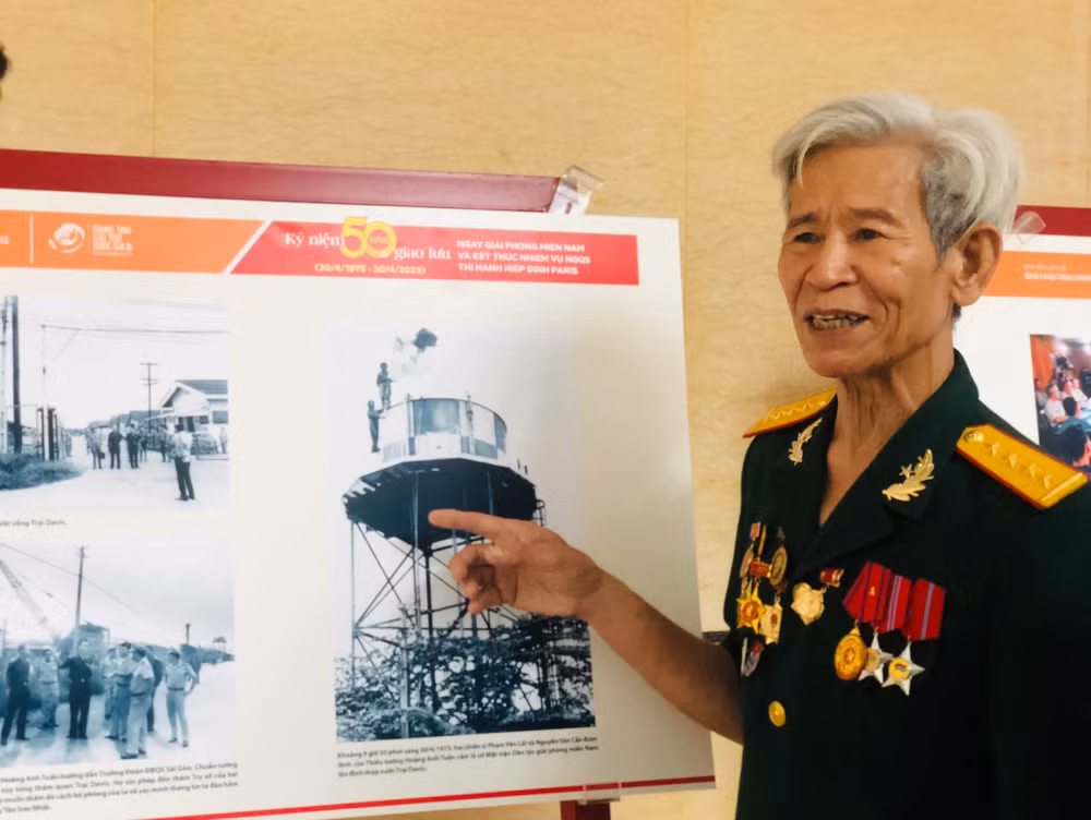 Cựu chiến binh Phạm Văn Lãi chỉ tay vào bức ảnh chụp ông treo cờ Giải phóng trên tháp nước ở Trại Davis.