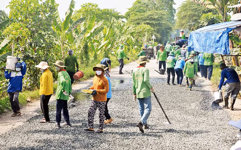 Sau khi trải nhựa, các thành viên trong đội chia nhau đi trải đá dăm bề mặt đường.