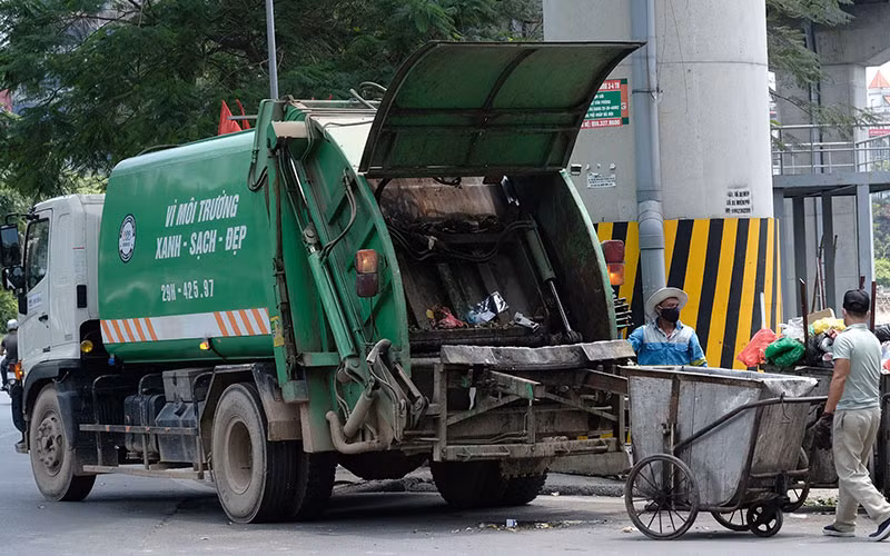 Công nhân Công ty Môi trường đô thị Hà Nội thu gom rác thải ở quận Đống Đa. (Ảnh PHẠM HÙNG)