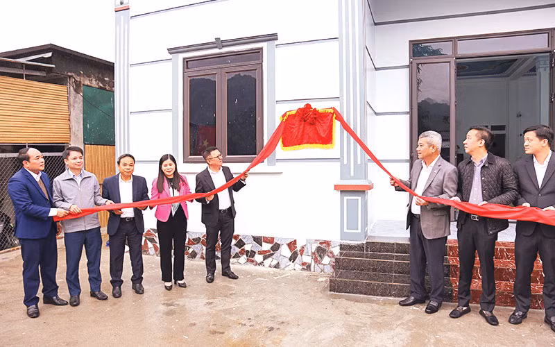 Đồng chí Lê Quốc Minh, Tổng Biên tập Báo Nhân Dân và các đại biểu gỡ băng khánh thành nhà Đại đoàn kết tại gia đình anh Đinh Văn Tinh.